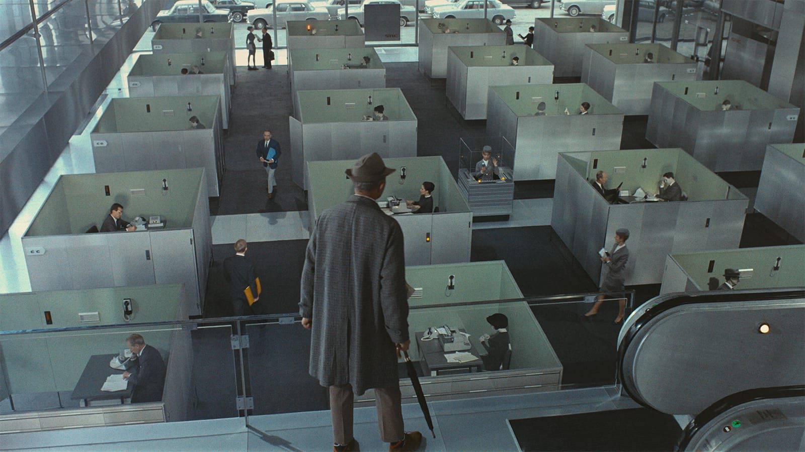 PlayTime filminde cam bölmelerin ve tekrarlanan ofis düzeninin içindeki insanları gösteren geniş kadraj.