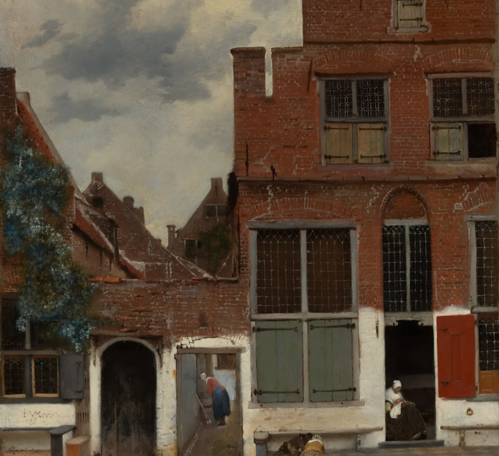 Brick houses, a narrow passage, and people in a quiet Delft street